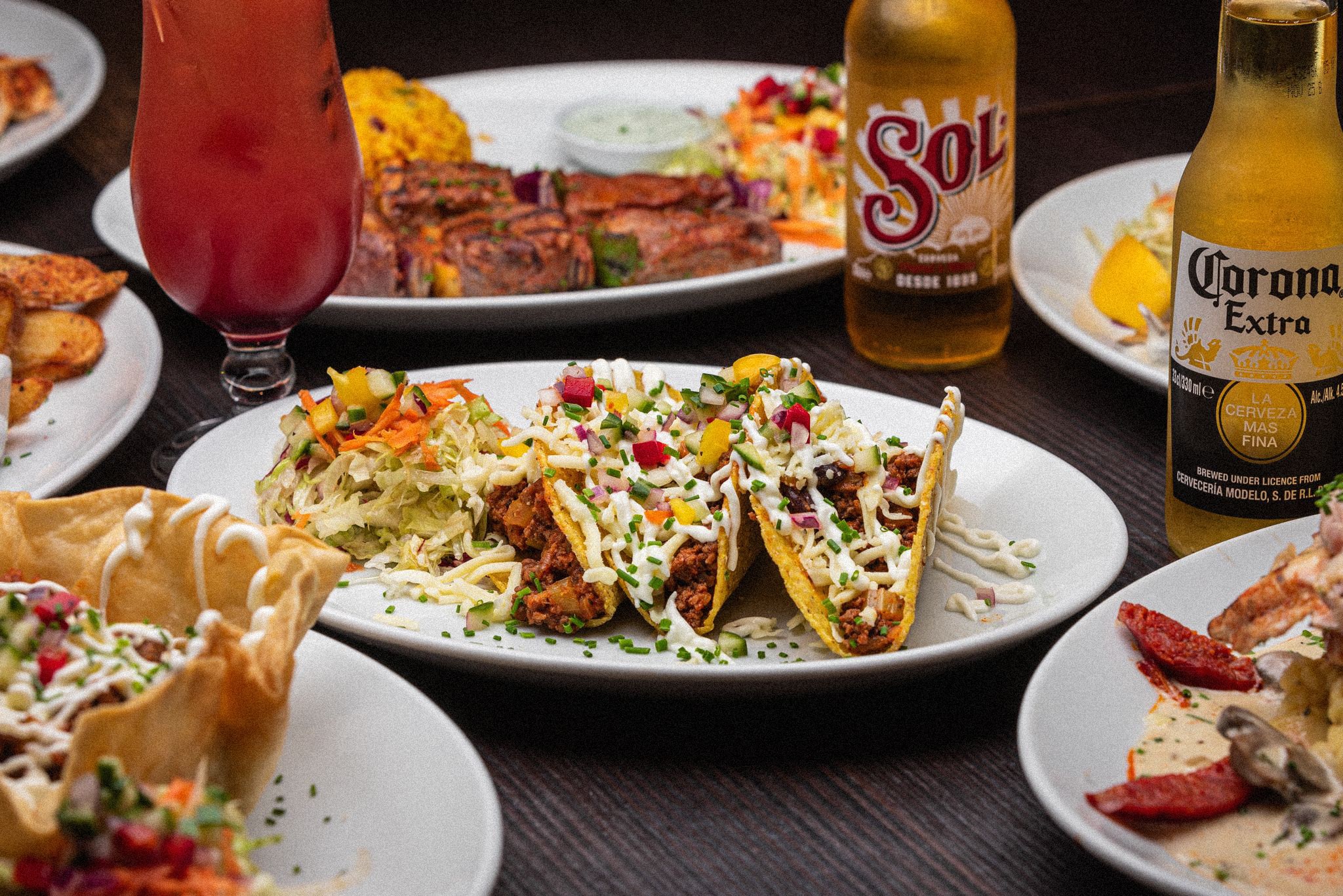 Plate of Mexican beef tacos topped with cheese and vegetables, served with slaw and bottles of Sol and Corona beer at La Parrilla restaurant in Waterloo Liverpool.